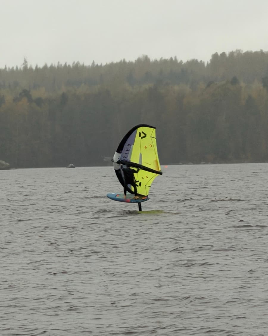 Jere wing foiling on a lake, lifted above the water on the foil